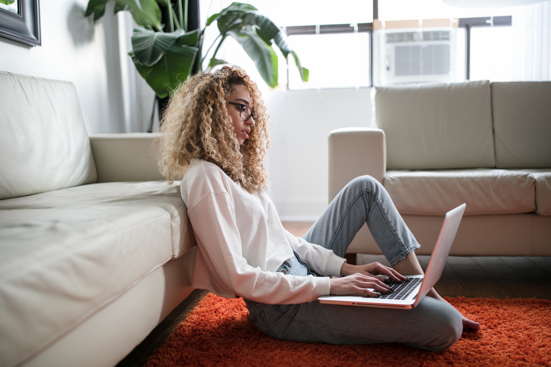 Woman working with laptop on the floor, trying to set up an effective home workspace.